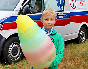 Chłopiec z watą cukrową na tle ambulansu medycznego